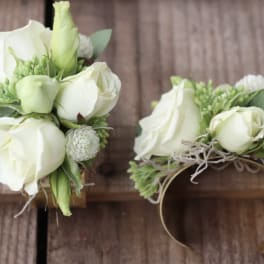 White rose wrist corsages with green accents on ribbon bands