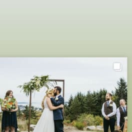 Bride and groom kissing under a floral wedding arch outdoors