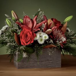 Red floral arrangement in a rectangular wooden box with lilies and roses