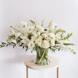 White floral arrangement in a clear glass vase on a small round table