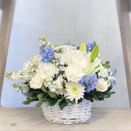 White and blue flower arrangement in a white wicker basket