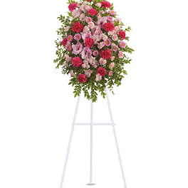 Standing floral spray with pink and magenta flowers on a white easel