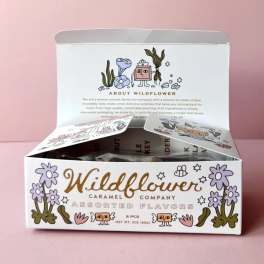 Open box of assorted caramels with floral illustrations on the packaging