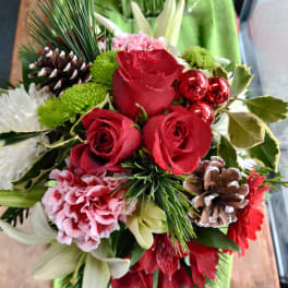 Bouquet of red roses, pink carnations, and white lilies with pinecones