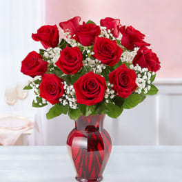 Red roses and white baby's breath in a red glass vase