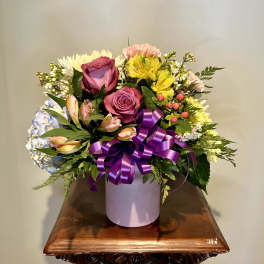 Mixed bouquet of roses, alstroemeria, and daisies in a lavender box with a purple ribbon