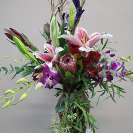 Tall bouquet of lilies, roses, and orchids in a vase