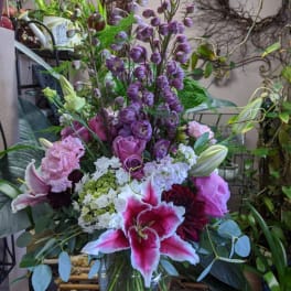 Mixed bouquet with pink lilies, roses, and purple blooms in a glass vase