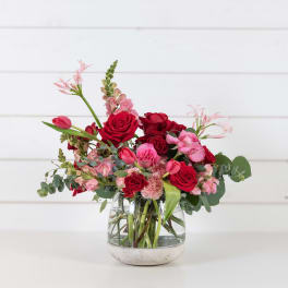 Mixed bouquet of red and pink flowers in a glass vase