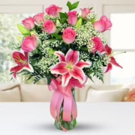 Pink roses and lilies in a glass vase with a pink ribbon