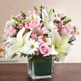 Pink roses and white lilies arranged in a clear glass vase