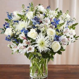 White and blue mixed bouquet in a clear glass vase