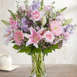 Pink roses and lilies arranged in a clear glass vase