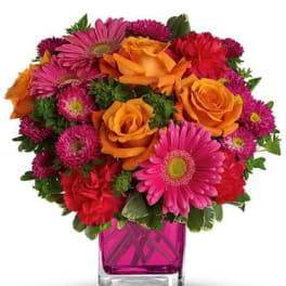 Bouquet of orange roses and pink daisies in a square glass vase