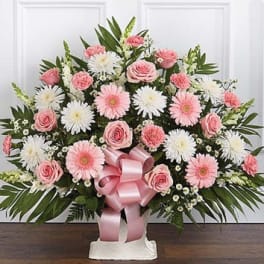 Pink and white floral standing spray with a pink ribbon on a white easel