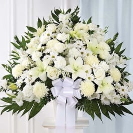 Large white funeral spray with lilies, chrysanthemums, and a ribbon