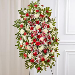 Standing floral spray with red and white flowers on a black easel