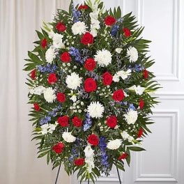 Standing floral spray with red roses, white mums, and blue flowers