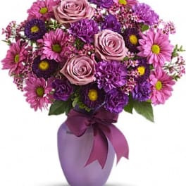 Pink and purple bouquet in a lavender vase with a ribbon