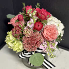 Mixed pink and white bouquet in a glass vase with a striped ribbon