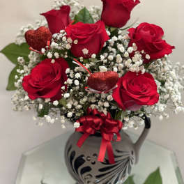 Red roses with baby's breath in a decorative vase and ribbon