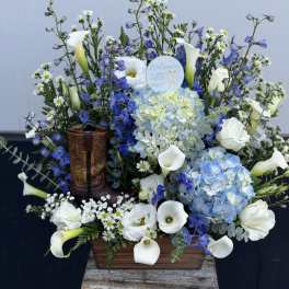 Blue and white floral arrangement with calla lilies and hydrangeas in a wooden container