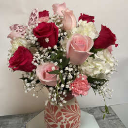 Bouquet of red and pink roses with white hydrangeas in a patterned vase