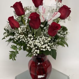 Red roses in a red glass vase with baby's breath and a butterfly decoration