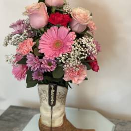 Pink roses and mixed flowers arranged in a cowboy boot vase