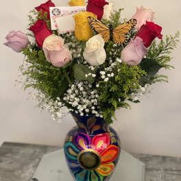 Bouquet of multicolored roses in a painted vase with a butterfly decoration