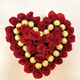 Heart-shaped arrangement of red roses and gold-wrapped chocolates