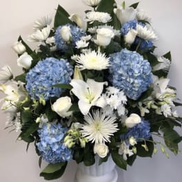 White lilies and roses with blue hydrangeas in a white vase