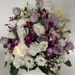 Lavender roses and white flowers arranged in a mirrored vase with an angel figurine