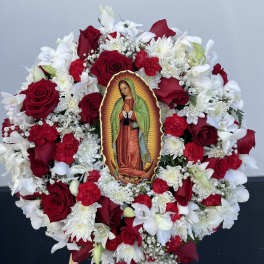 Circular floral wreath with red roses, white flowers, and a Virgin of Guadalupe image