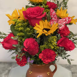Bouquet of red roses and yellow sunflowers in a painted ceramic vase