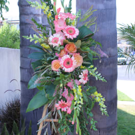 Tall floral spray with pink gerbera daisies and peach roses on a stand