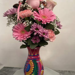 Pink and lavender flower arrangement in a colorful painted vase