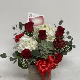 Red roses and white hydrangeas in a wooden box with a red ribbon.