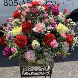 Large mixed flower arrangement in a basket on a stand