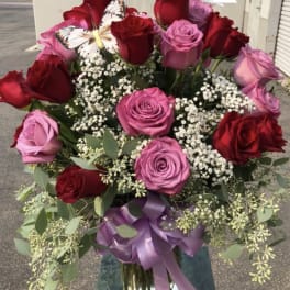 Bouquet of red and pink roses in a glass vase with a purple ribbon