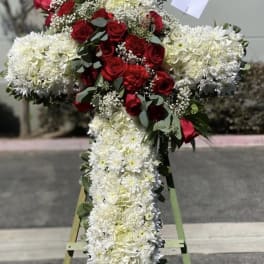 Cross-shaped floral tribute with red roses and white flowers