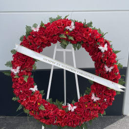 Large red rose funeral wreath on a stand with a white ribbon