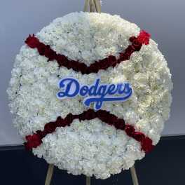 Round floral tribute of white flowers with red rose stripes and a Dodgers sign