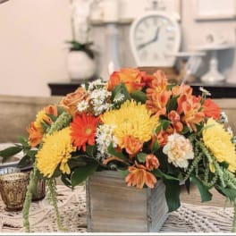 Orange and yellow floral arrangement in a wooden box centerpiece