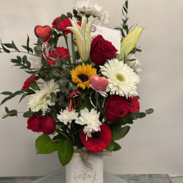 Mixed bouquet of red roses, white lilies, and daisies in a white vase