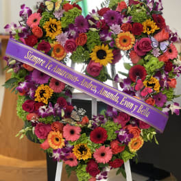 Heart-shaped floral wreath on an easel with a purple memorial ribbon
