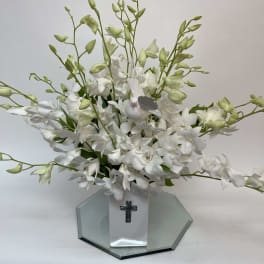 White orchid arrangement in a square vase with a cross emblem