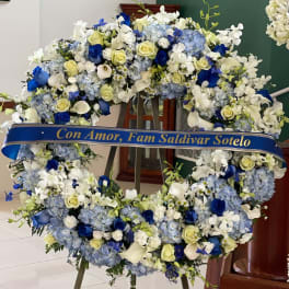 Large blue and white floral wreath on an easel with a memorial ribbon