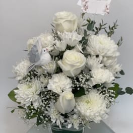 White floral arrangement in a clear vase with a small dove decoration