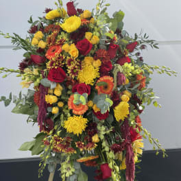 Large standing floral spray with red, yellow, and orange blooms on an easel